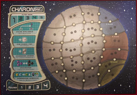 The game board for Charon Inc. Most of the board is a representation of a small moon, subdivided into twenty-one areas, all but one of which have one, two, or three eight-point star icons. The intersections of the borders have circle icons, and the midpoint of each side of each area also has a circle icon. The left side of the board has a number of other spaces; at the top of this section is the player order, with five numbered spaces. Below that are five spaces for special actions, from top to bottom: stolen intelligence, rare mineral find, engineering advance, synchrotron, and underground warehouse. At the bottom is another track, labelled 'round,' with four numbered spaces.