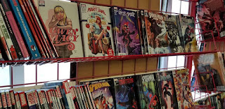 Comic books sit on red wire racks at Acme Comics in Sioux City