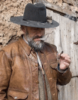 Animation of a western man wearing a cowboy hat and orange brown leather jacket blowing out smoke