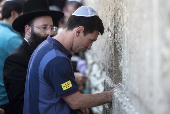 Barcelona player Lionel Messi puts a paper with wishes in a crack of the Western Wall