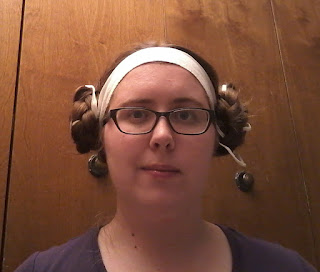 The author wearing a white linen headband (fillet) with a large braided bun on either side of her head. 