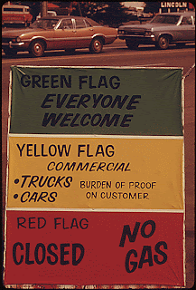 Image of sign put out by a gasoline dealer in Oregon, USA, explaining the flag policy during the fuel crisis in the winter of 1973-1974. As the sign says, the green flag means that anyone can buy gas, the yellow sign means only commercial vehicles can buy gas, and a red flag means that there is no gas at all for sale. This image is available from the Archival Research Catalog of the National Archives and Records Administration under the ARC Identifier 555518. This image was sourced through Wikimedia and is in the public domain in the United States because it is a work of the United States Federal Government under the terms of Title 17, Chapter 1, Section 105 of the US Code.