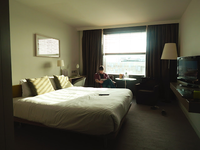 Hotel room with a man sitting a reading a magazine