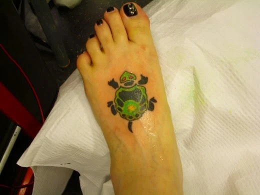 vemos a una mujer con los pies desnudos , lleva un tatuaje en el pie 