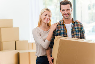 Smiling young couple holding moving boxes