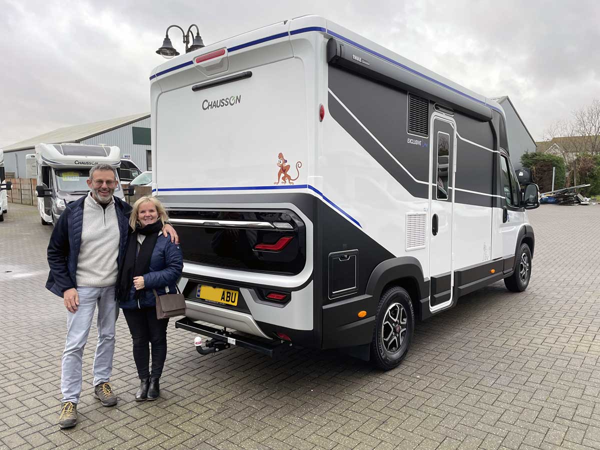 Couple standing behind new motorhome