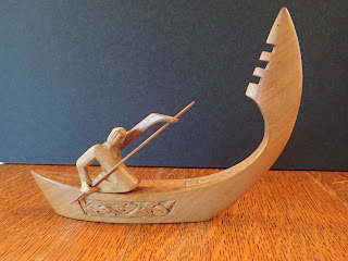 wooden model boat propelled by a kneeling paddler