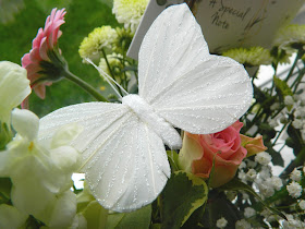 A photo of a glittery butterfly pick in a bouquet of flowers 