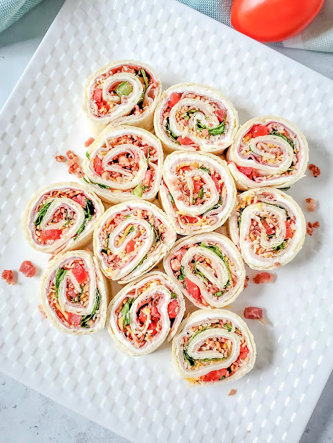 sliced pinwheels on a white square plate with bacon bit garnish.