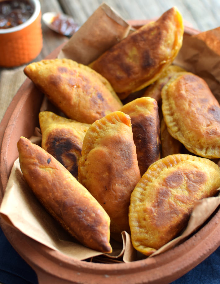 Samosas de papa y zanahoria al curry, servidas en una bandeja de barro cocido