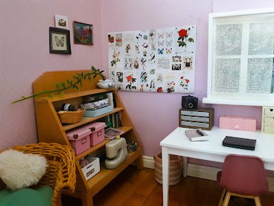 One-twelfth scale modern miniature craft and reading corner with a study table, old greengrocer's shelving unit and a cane rocking chair.
