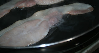 The bacon sizzling in the frying pan