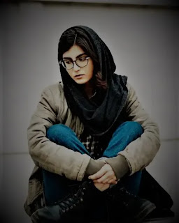 An image of a girl in spectacles sitting very alone and sadly
