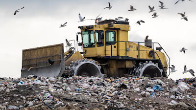dumber truck on a landfill site with seagulls surround all the rubbish