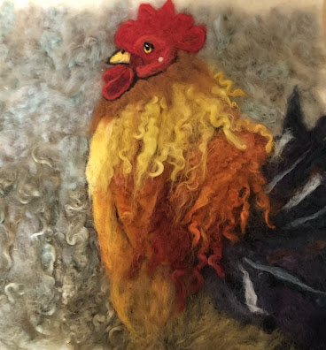 Photo of a two-dimensional needle-felted portrait of a rooster against a gray background. It is constructed from carded wool and locks. The rooster's plumage is red, orange, yellow, and indigo with white highlights.