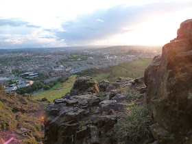 Uitzicht vanaf Arthur's Seat over Edinburgh met heuvels en ondergaande zon op achtergrond