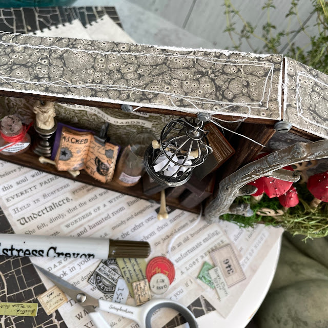 The Devious Botanist Halloween Vignette made with: Tim Holtz coffin vignette, backdrops, stickers, curiosities, curator labels, corked vials, corked domes, birdcage, toadstools, candle stands, drippy candles, bubbles, spider, hardware heads, tiny clips, mini books ephemera, villainous potion, mr. bones