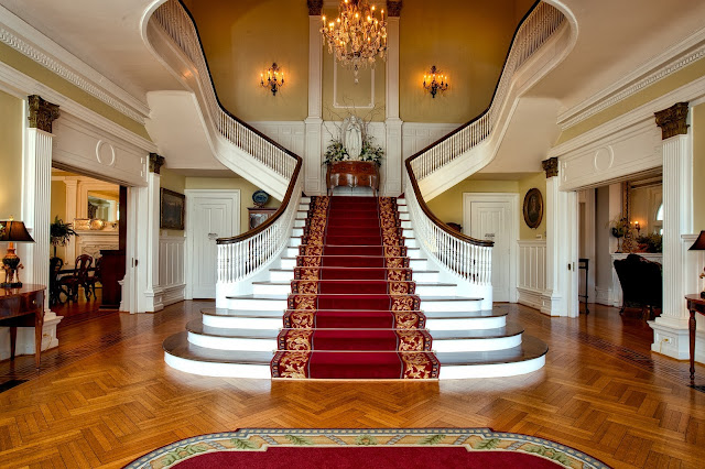 a grand staircase with red carpet and chandelier