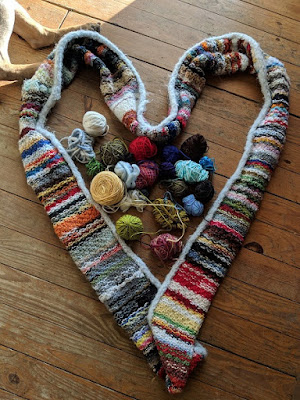 an infinity scarf in the shape of heart made from scrap yarn with small remnants of yarn in the middle