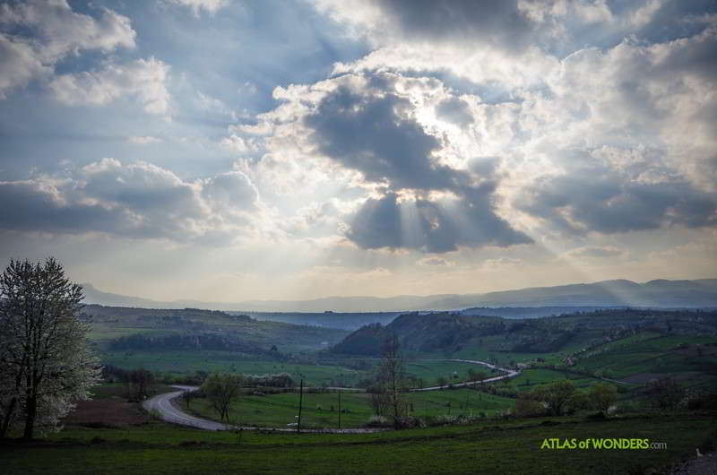 Windy road in Transylvania with rays of sun and clouds