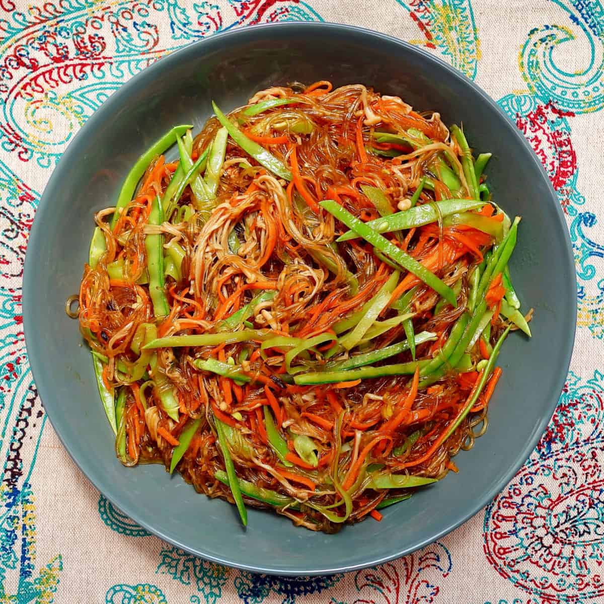 Stir-Fried Cellophane Noodles with Enoki Mushrooms in a dark bowl.