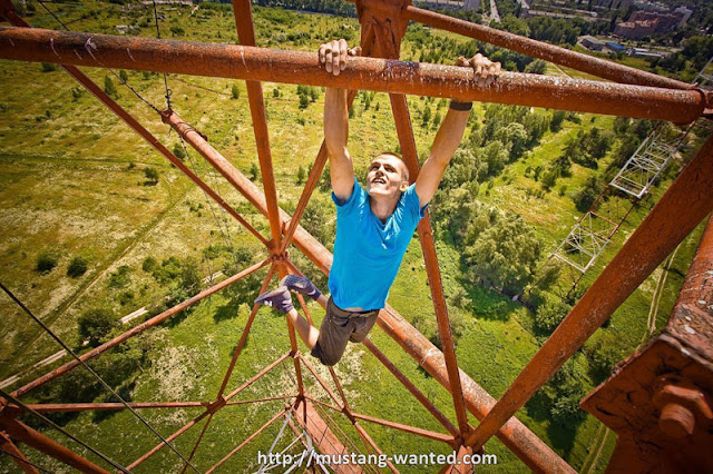 Man hanging from the tall steel object 