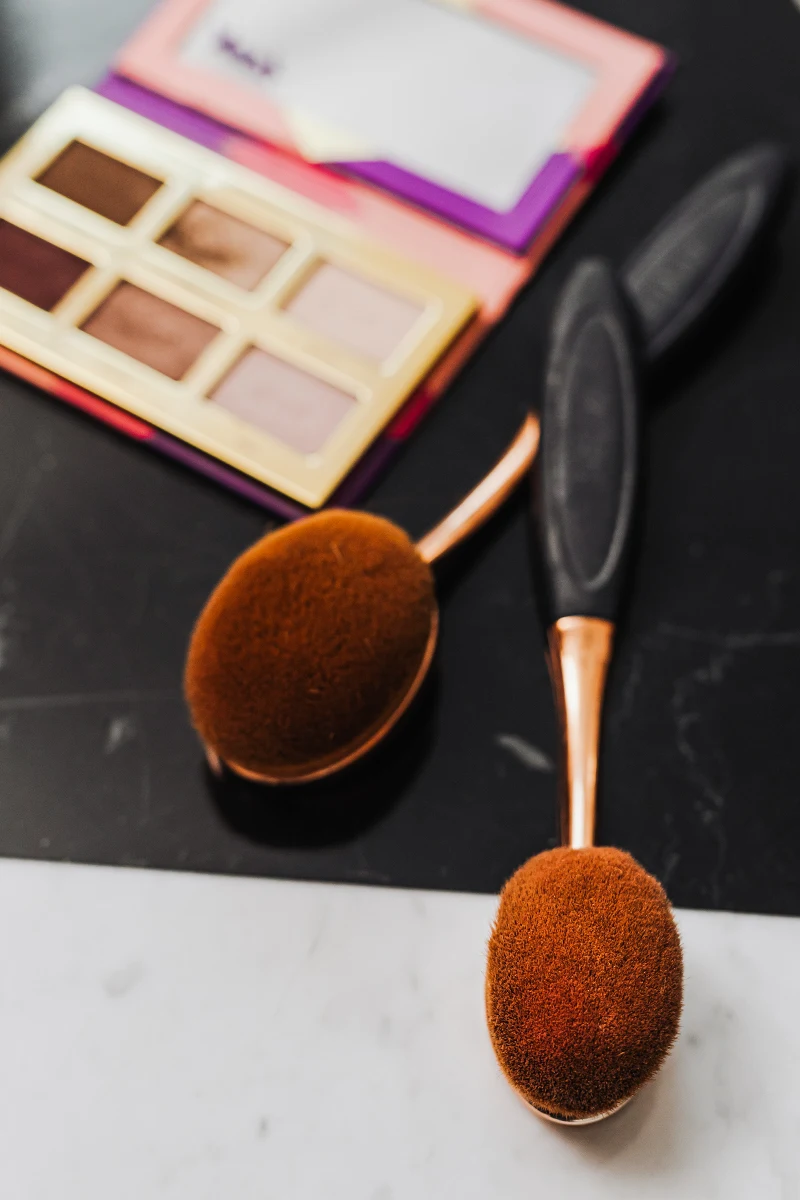 two toothbrush makeup brushes on top of an opened eyeshadow palette