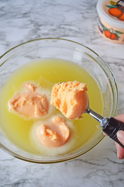 hand scooping sherbet into glass punch bowl.