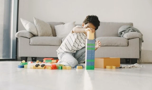 صبي يبني برجًا من المكعبات من اجل تعلم فنون البناء