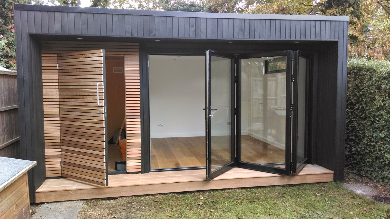  room with contrasting cedar cladding and bi-fold doors and decking