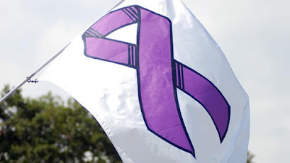 Una bandera blanca con un dibujo de un lazo morado en el centro