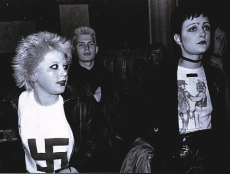 Siouxsie Sioux with a young Billy Idol in the background.  PunkMetalRap.com