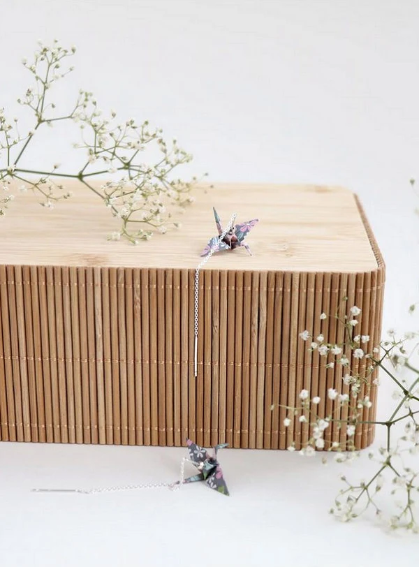 pair of patterned paper origami crane threaders displayed on wooden box decorated with dried flowers