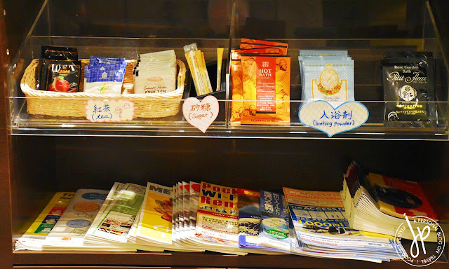 shelf with tea packets, bathing powder, and travel brochure