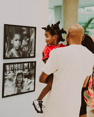 Photo of Man holding a toddler, viewing photos from Look! Exhibit