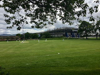 People playing cricket with Murrayfield Stadium behind them.