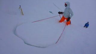 Winter mountaineering abseiling off a snow bollard