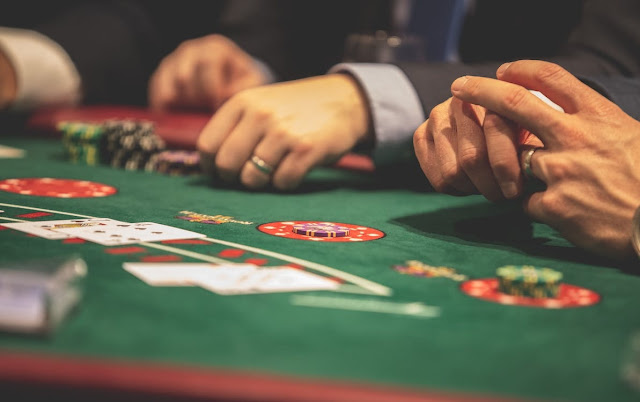 the hands of two men with rings on their hands on the black jack table