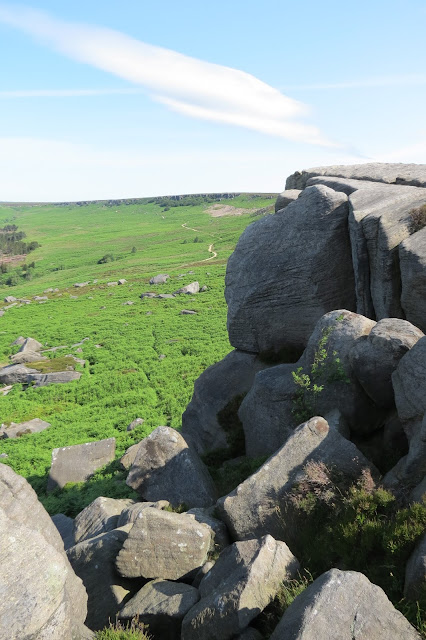 A view across moorland from the southern end of the escarpment to the northern end. Large rock formations fill the right hand side of the picture.