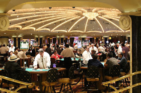 A room in a casino filled with blackjack tables, all busy with players and dealers.
