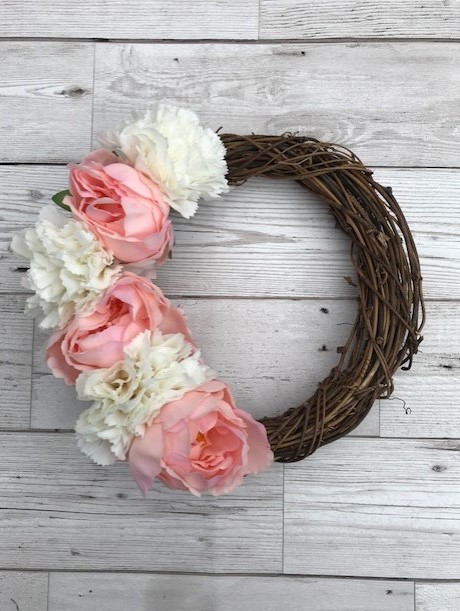 Rattan wreath with pink and white flowers down one side