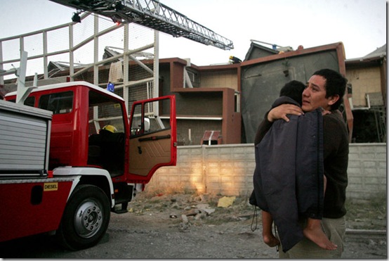 A man carries a child next to a damaged building in Concepcion, Chile, Saturday Feb. 27, 2010 after an 8.8-magnitude struck central Chile. The epicenter was 70 miles (115 kilometers) from Concepcion,  Chile's second-largest city.(AP Photo)