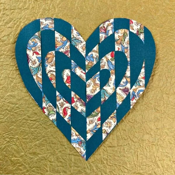 woven paper heart made of decorative papers displayed on gold textured paper