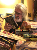 Man examining a book with piles of books in foreground
