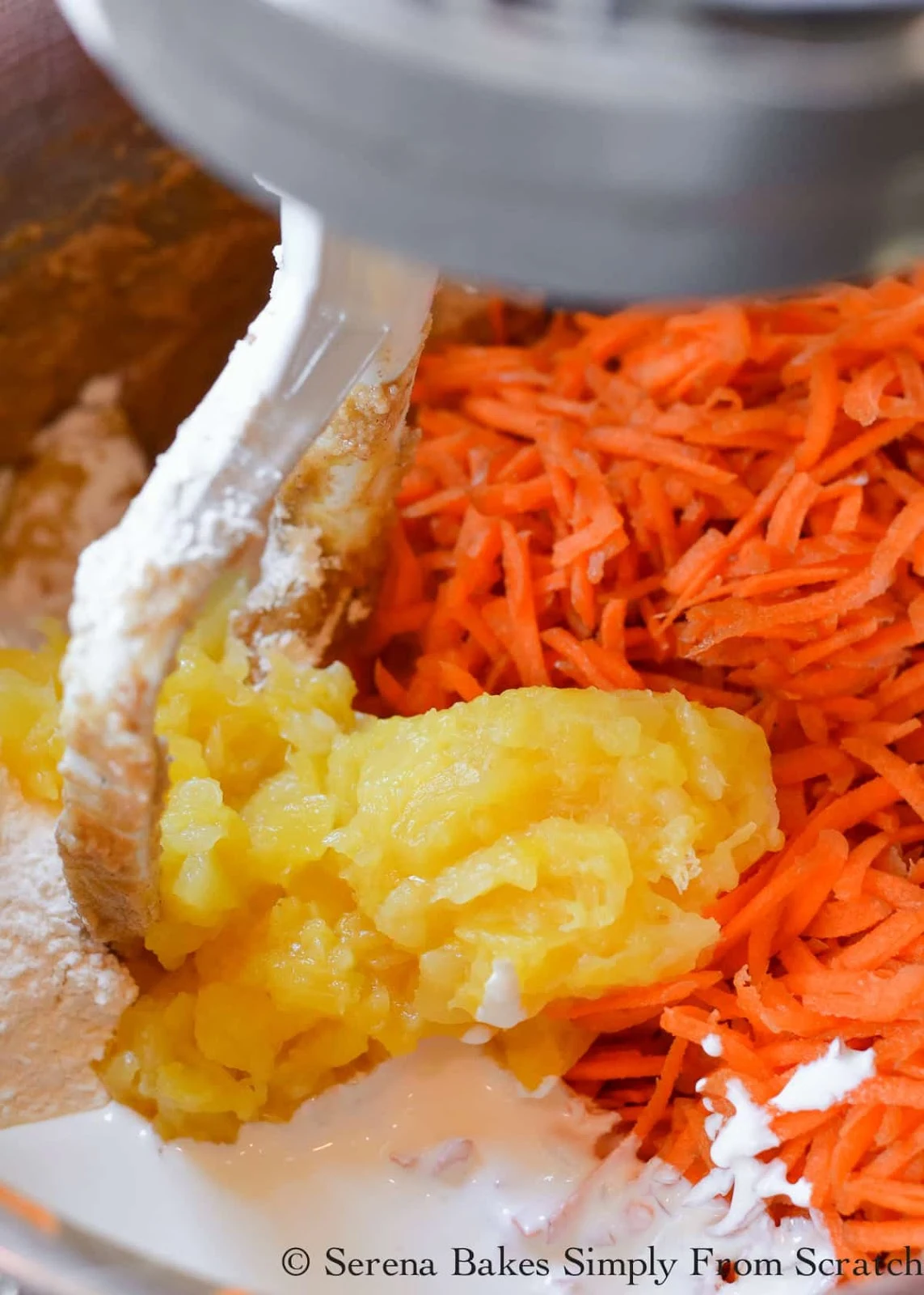 Carrot Cake batter with sour cream, all-purpose flour, grated carrots and crushed pineapple in a large stainless steel mixing bowl.