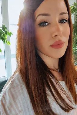 Foto de Yanira en la oficina sonriendo, sentada frente al ordenador, mientras escucha uno de sus podcasts favoritos