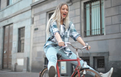 A woman happily riding a bicycle through a city with her feet off the pedals