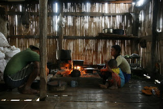 Sunny kokkaa illallista majapaikassamme Red Lahu heimon kodissa. Kuvassa hyvin tuulettu keittio varusteineen. Vasemmalla seinallinen valkoisia maissisakkeja
