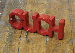 3D ouch word with nails inserted coming out