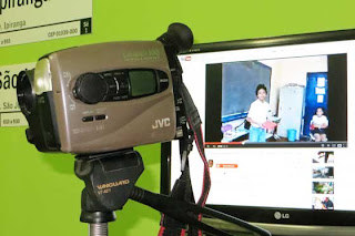 Foto da filmadora em frente ao monitor do computador que passa o vídeo no Youtube